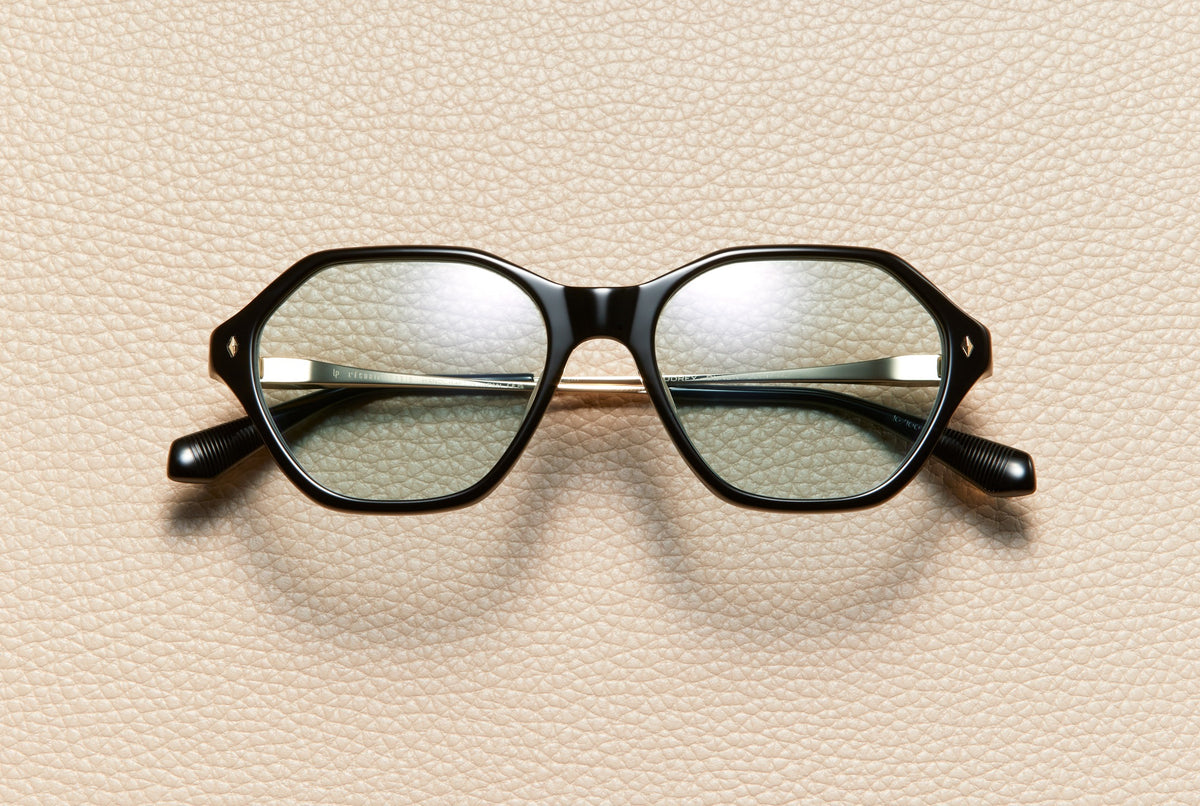 Audrey Black sunglasses by L'Écurie Paris, hexagonal polished black acetate frame with dusty blue lenses and 18K gold-plated titanium temples