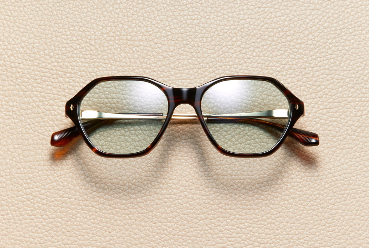Audrey Fire sunglasses by L'Écurie Paris, hexagonal red-brown fire acetate frame with dusty blue lenses and 18K gold-plated titanium temples