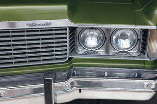 Chrome grille and twin headlights of a green vintage car