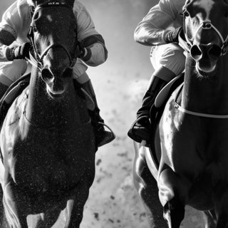 Two racehorses and jockeys at full gallop, black and white