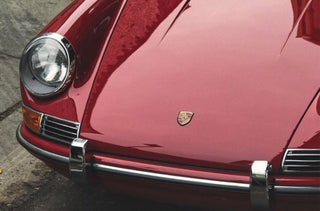 Round headlight and hood of a red vintage sports car